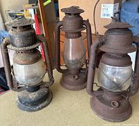 Three vintage coal oil lamps with metal and glass, two branded Beacon, all heavily rusted and dirty.