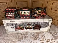 Front view of three-piece porcelain Christmas train set displayed on top of box showing the set and box image.