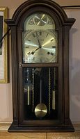 Full view of the wooden Citizen wall clock with closed glass door showing pendulum and weights inside.