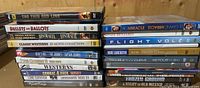 Close-up photo showing a stack of assorted DVD cases focused on western and war movie titles.