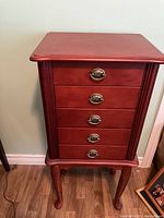 Front view of a solid wood 5-drawer jewelry tower with metal drawer handles, standing on four legs.