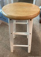 Top view of stool showing round natural wood seat and white legs.