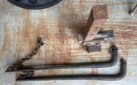 Two 2-inch diameter metal sway bars with attached chains, showing rust and wear, placed on a wooden surface with rust stains.