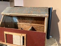 Handmade wooden barn showing hinged top and sliding door open, revealing interior compartments.