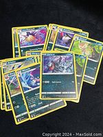 Photo showing 11 Pokémon trading cards with teal/blueish colored backgrounds and various Pokémon illustrations.