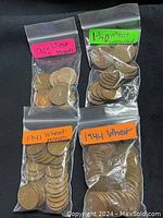 Four resealable plastic bags each labeled with a year containing 1940s copper Wheat Pennies (1940, 1941, 1942, 1944). Bags show a sizable quantity of coins.