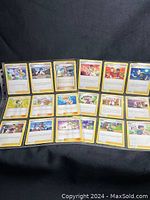 Front view of 15 Pokémon Trainer cards in sleeves, showing character art and text details.