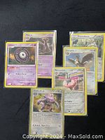 Full view of six sleeved Pokémon cards displayed on dark surface showing character images and text