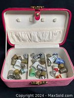 Open view of the pink and red travel box filled with assorted vintage thimbles inside
