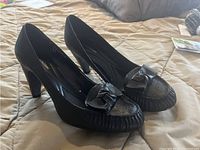 Black leather high-heeled shoes showing front and side view with bow decoration