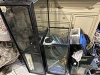 Photo showing four glass aquariums of different sizes stacked vertically with black trim and some aquarium accessories on the side.