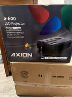 Front of original box showing Axion a-600 LED Projector model and features