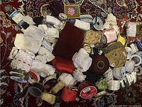 Overhead photo of mixed assortment of ribbons, lace trims, and seam bindings laying on a patterned rug.