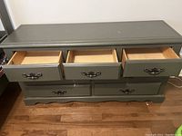 Full view of grey wooden dresser showing open top three drawers and four bottom drawers with metal handles.
