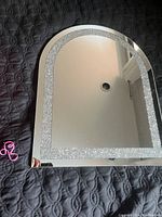 Full view of the dome shaped mirror showing the sparkling trim around the glass edge with the reflection of ceiling and room corner visible.