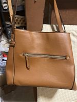 Front view of tan handbag purse showing smooth leather finish and external zippered pocket with adjustable strap.