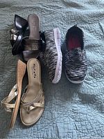 Photo of three pairs of women's shoes size 8 including black sandals, gold strappy sandals, and knit pattern slip-on sneakers