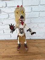 Front view of the full Kachina statue showing the fur head, yellow eyes, and painted body