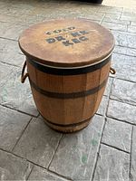 Wooden keg barrel labeled 'COLD DRINK KEG' on lid, showing wood texture and rope handles on sides.