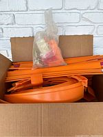 Box with orange plastic Hot Wheels Sizzlers track pieces and accessories packed inside.