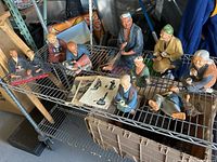 Eight clay sculptures of elderly Japanese men and women in various poses on metal shelving, showing their detailed facial features, traditional clothing colors and some aged paint wear.