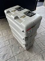 Side view of large gray Pelican case standing vertically, showing two black handles and two metal latches on top.
