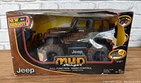 Front view of the New Bright Mudslinger Jeep RC toy in original packaging with box torn and dirty.