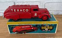 Red metal Texaco fuel truck replica, with visible Texaco lettering, coin slot on top, and original box underneath, showing the branding and year 1939.