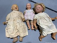 Photo of all three antique dolls laid side by side, showing their size differences and dresses.