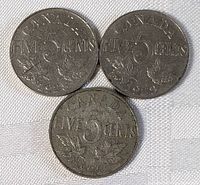 Three Canadian five cents coins laid on fabric surface, showing the side with denomination, year, and maple leaf design.