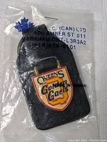 Front view of the Queen's University Golden Gaels keychain still sealed in clear plastic packaging showing logo and manufacturer info.
