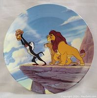 Front view of The Lion King collector's plate showing Rafiki holding baby Simba on Pride Rock with Mufasa and Sarabi