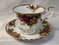 Front view of the Royal Albert teacup placed on its matching saucer, showing floral pattern and gold rim.
