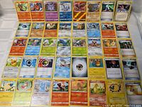 Photo of 60 assorted Pokémon cards arranged in 6 rows and 10 columns, showing a variety of Pokémon and energy cards with some foil/holo finish.