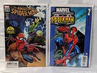 Photo of two Marvel Spider-Man comic books in plastic sleeves showing front covers