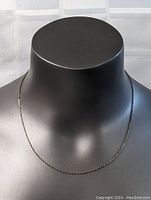 Image showing the full front view of the sterling silver necklace displayed on a black mannequin bust, illustrating the chain's length and link style.