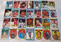 Top view of 25 vintage NHL hockey cards spread out showing various players and teams with colorful borders typical of cards from the 1970s-1980s.