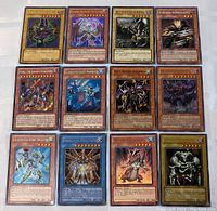 Top-down photo showing all 12 Yu-Gi-Oh foil trading cards laid out in a grid, clear view of cards' art and foil details.