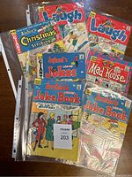 Eight vintage Archie comic books arranged on a wooden surface. Covers display colorful comic art with some wear and damage, including creases and discoloration.
