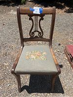 Front view of the vintage wooden chair showing carved backrest and light blue floral cross-stitch seat upholstery.
