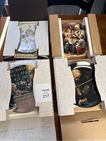 Four decorative plates still in their original cardboard packaging, showcasing vintage style artwork.
