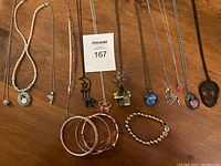 Overview of all necklaces and bracelets laid out on wooden surface, showing variety of chains and pendants including Disney items.
