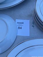 Stack of white plates with gold rim visible on edge.