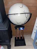 Photo showing full height of the globe on its black metal and wooden stand against a brown backdrop.