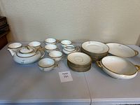 Full set displayed on table including teapot, cups, saucers, plates, and serving bowls.