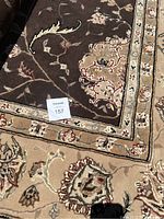 Close-up of the corner showing floral and vine pattern on a dark brown field with beige floral border.