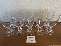Ten clear glass water goblets in a row showing their size and shape.
