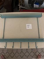 Front view of the painted vintage metal wall shelf with hooks, showing decorative lattice trim and five hooks.