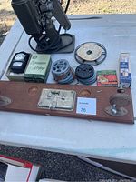 Full overview of vintage movie equipment and accessories including the wooden mounting board, film reels, exposure meter box, and coiled electrical cord