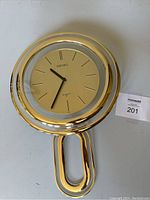 Front view of Seiko wall clock with gold-tone frame and pendulum, clock face shows time, clock is working.